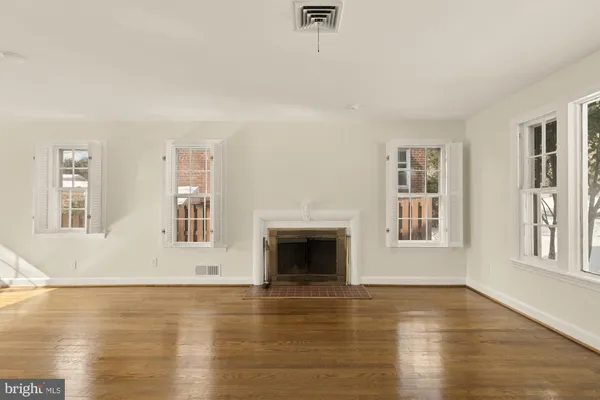 a view of an empty room with window and wooden floor