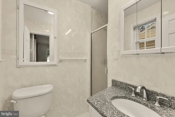 a bathroom with a granite countertop toilet a sink and mirror