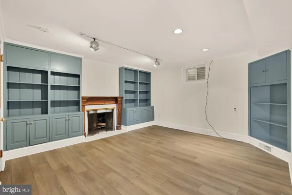 an empty room with wooden floor fireplace and windows