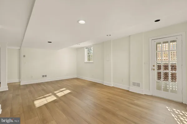 a view of an empty room with wooden floor and windows