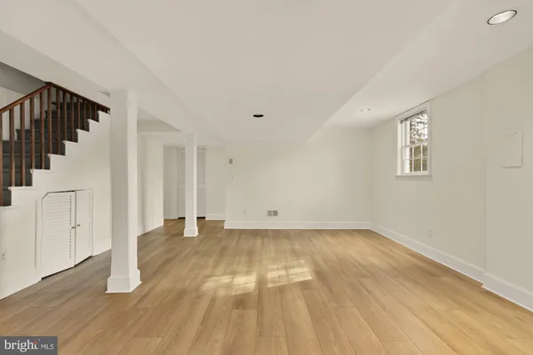 a view of an empty room with wooden floor and stairs