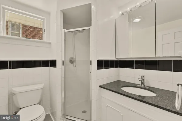 a bathroom with a granite countertop sink toilet a mirror and shower