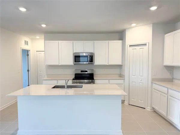 a kitchen with stainless steel appliances a refrigerator sink and white cabinets