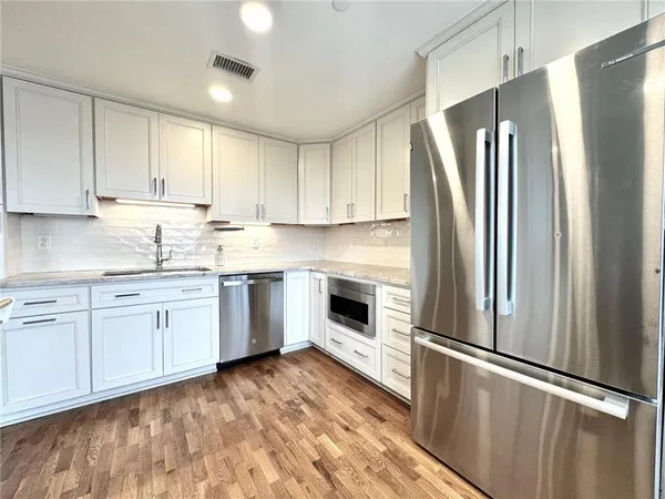 a kitchen with granite countertop stainless steel appliances a refrigerator sink and cabinets