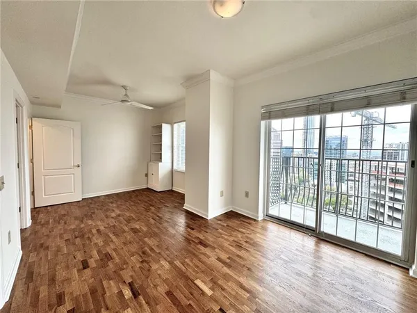 a view of empty room with wooden floor and fan