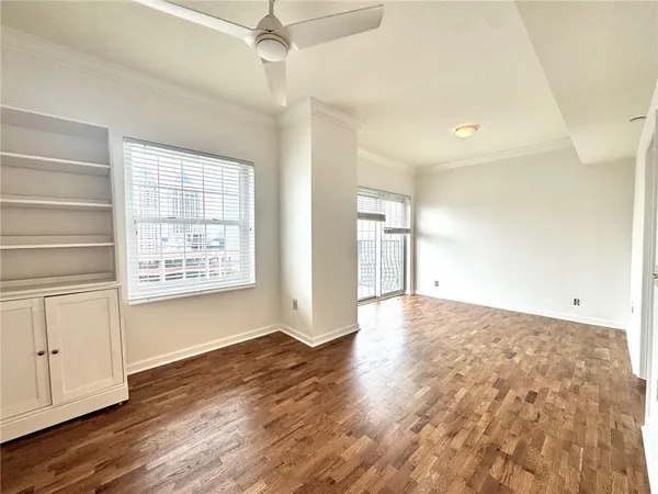 a view of an empty room with wooden floor and a window