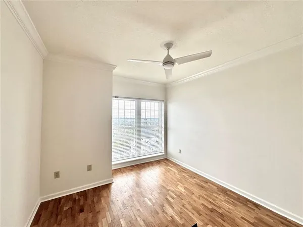 an empty room with wooden floor fan and windows