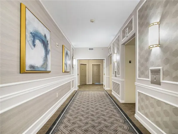 a view of a hallway with wooden floor and a bathroom