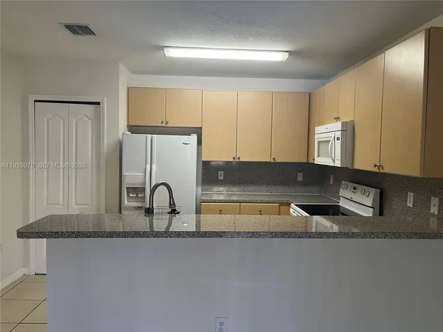 a kitchen with granite countertop a sink a stove and a refrigerator