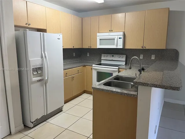 a kitchen with a refrigerator sink and cabinets