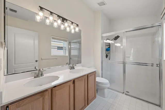 an empty room with wooden floor chandelier fan and windows
