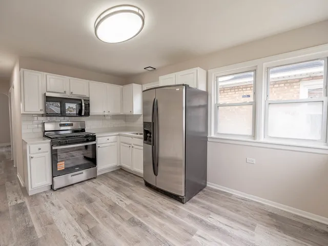 a kitchen with stainless steel appliances a refrigerator a stove cabinets and a sink