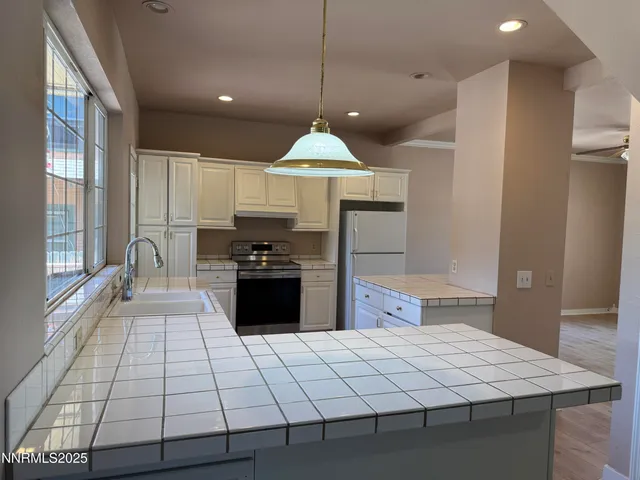 a large kitchen with a stove a sink dishwasher and a refrigerator with wooden floor