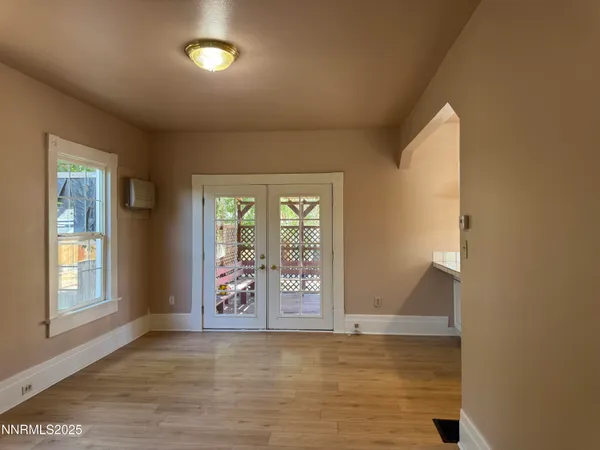 a view of an empty room with window and wooden floor