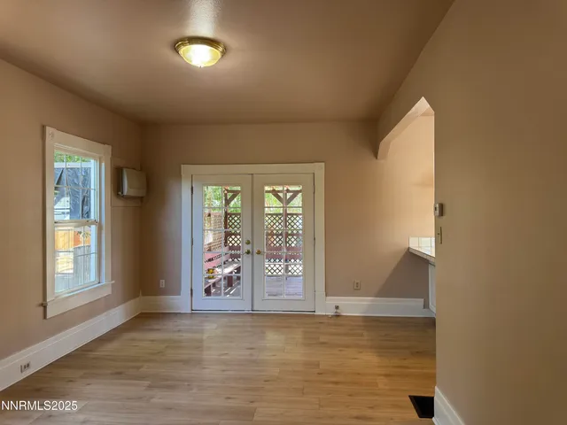 a view of an empty room with window and wooden floor