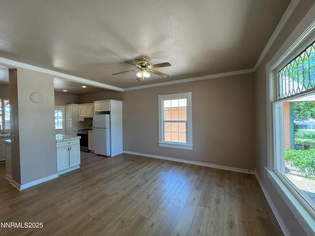 a view of an empty room with a window and wooden floor