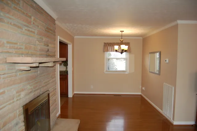 a view of empty room with wooden floor and fireplace