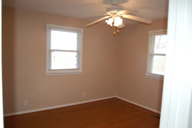 an empty room with windows and fan