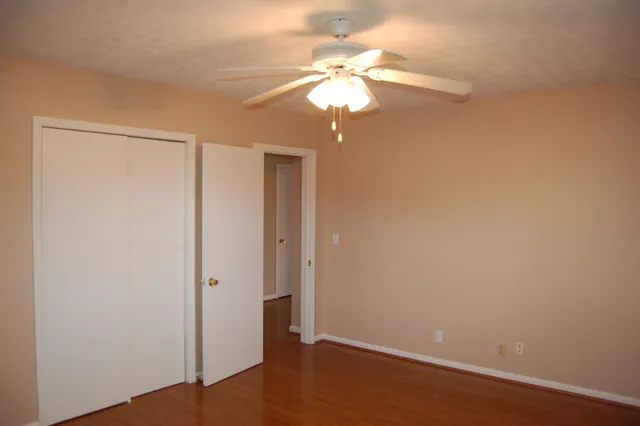 an empty room with wooden floor and chandelier fan
