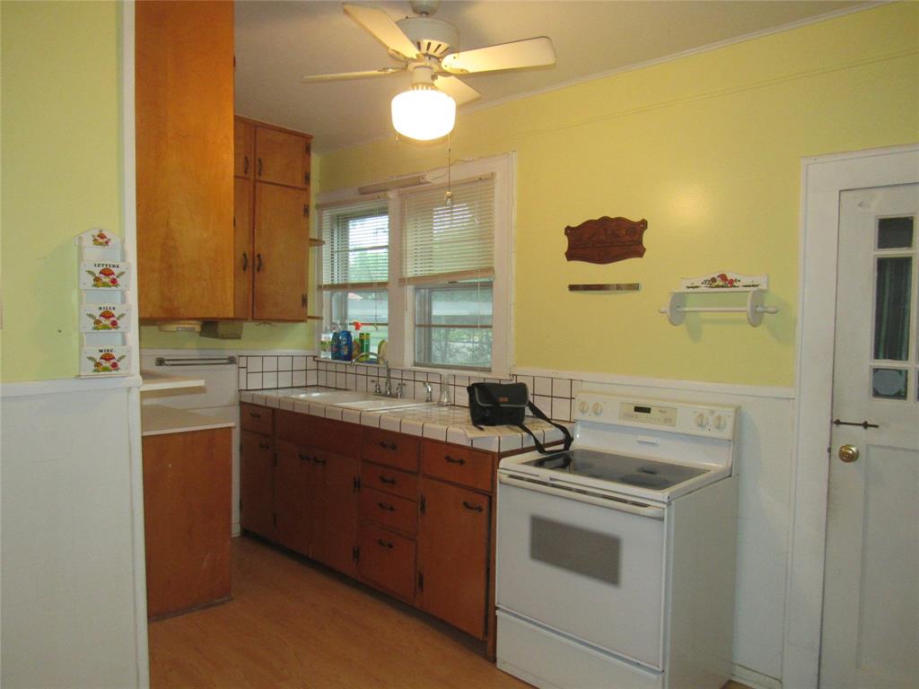 101 East Murray Street Denison, TX 75021 - Photo 15 of 32 a kitchen with a stove cabinets and a refrigerator