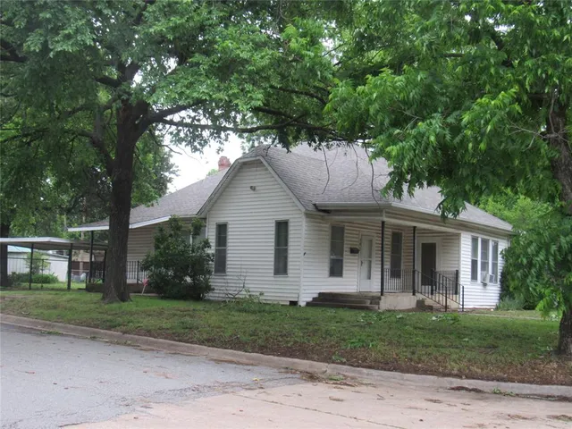 a view of a yard in front of a house with large trees
