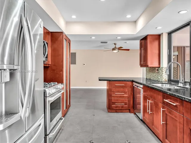 a kitchen with stainless steel appliances granite countertop a refrigerator and a stove