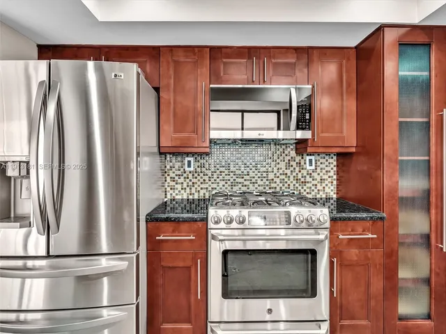 a kitchen with stainless steel appliances wooden cabinets and a stove top oven