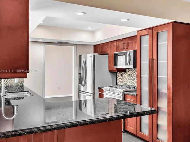 a kitchen with stainless steel appliances granite countertop a refrigerator and a sink