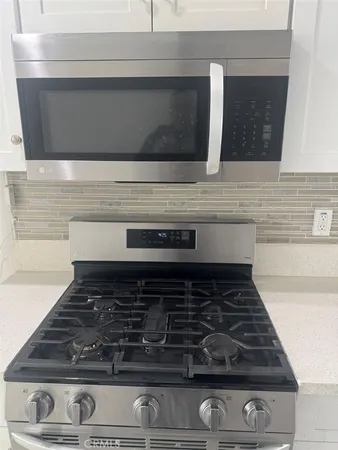a kitchen with granite countertop a stove top oven and cabinets
