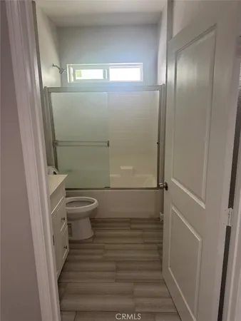 a view of an empty room with wooden floor and closet
