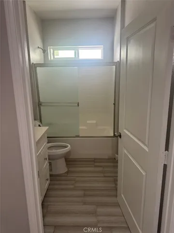 a view of an empty room with wooden floor and closet