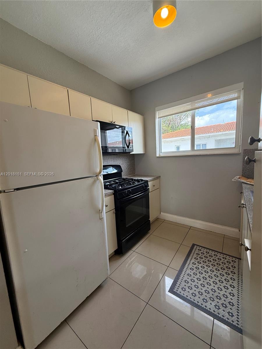 7710 Harding Avenue, Unit 1 Miami Beach, FL 33141 - Photo 9 of 10 a kitchen with stainless steel appliances a refrigerator sink and stove
