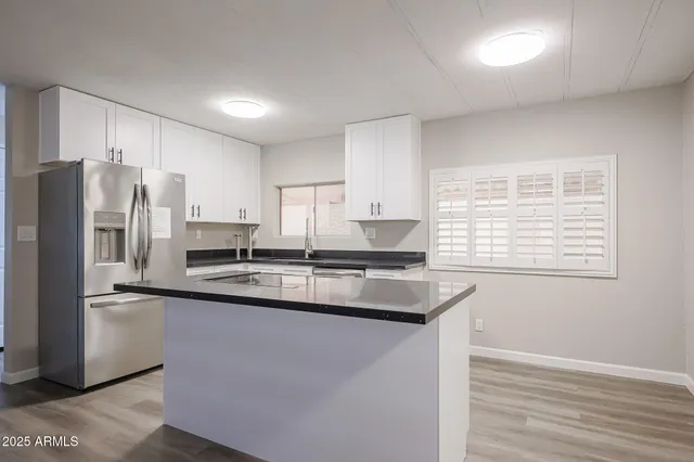 a kitchen with stainless steel appliances granite countertop a sink a stove a refrigerator a center island and cabinets