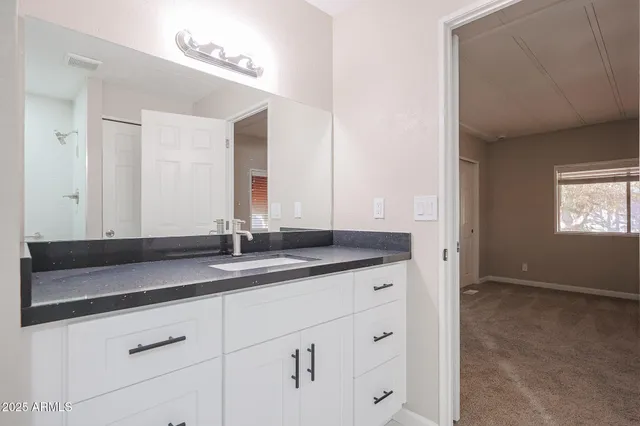 a bathroom with a granite countertop sink and a mirror
