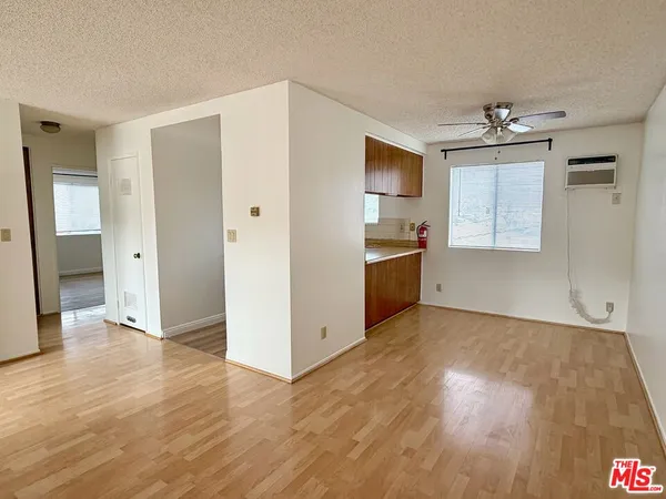 an empty room with wooden floor cabinet and windows