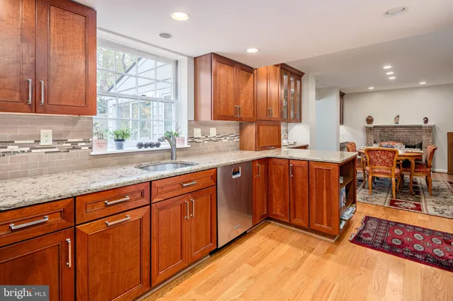 a kitchen with stainless steel appliances granite countertop wooden cabinets a sink and dishwasher with a large window