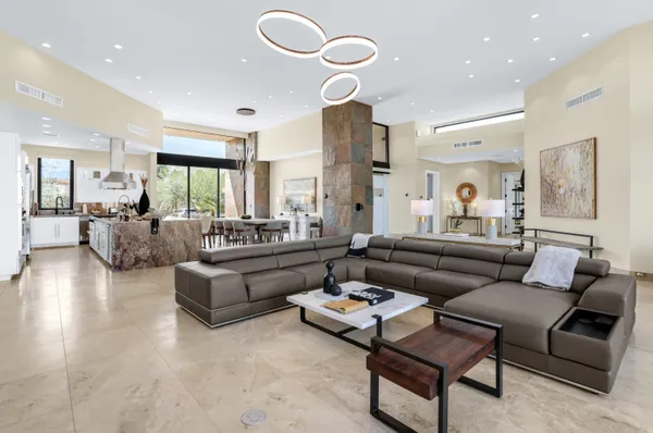 a living room with furniture kitchen view and a large window