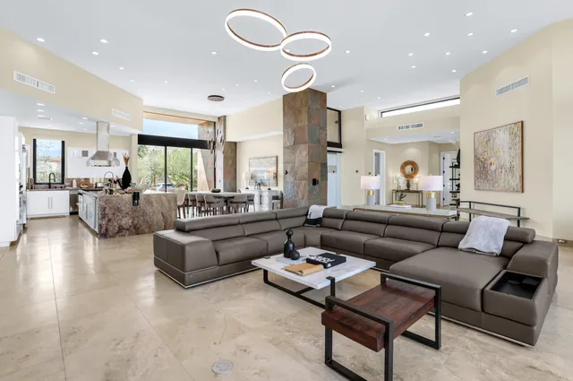 a living room with furniture kitchen view and a large window