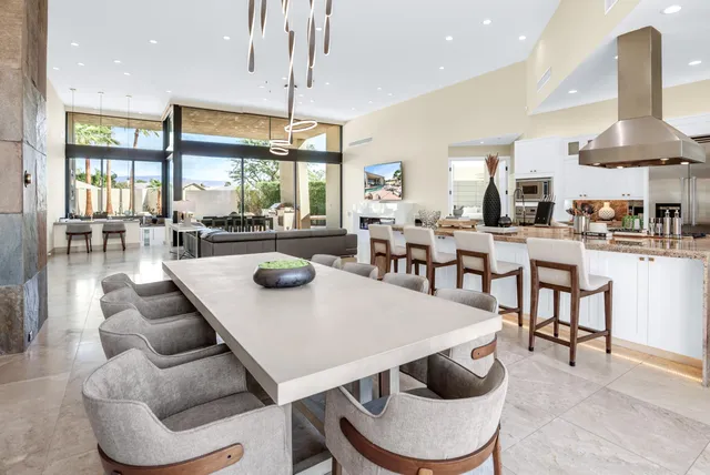 a kitchen with stainless steel appliances granite countertop a table chairs stove a sink dishwasher and cabinets