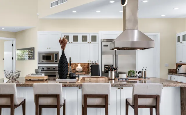 a kitchen with stainless steel appliances granite countertop a stove top oven a sink a dining table and chairs