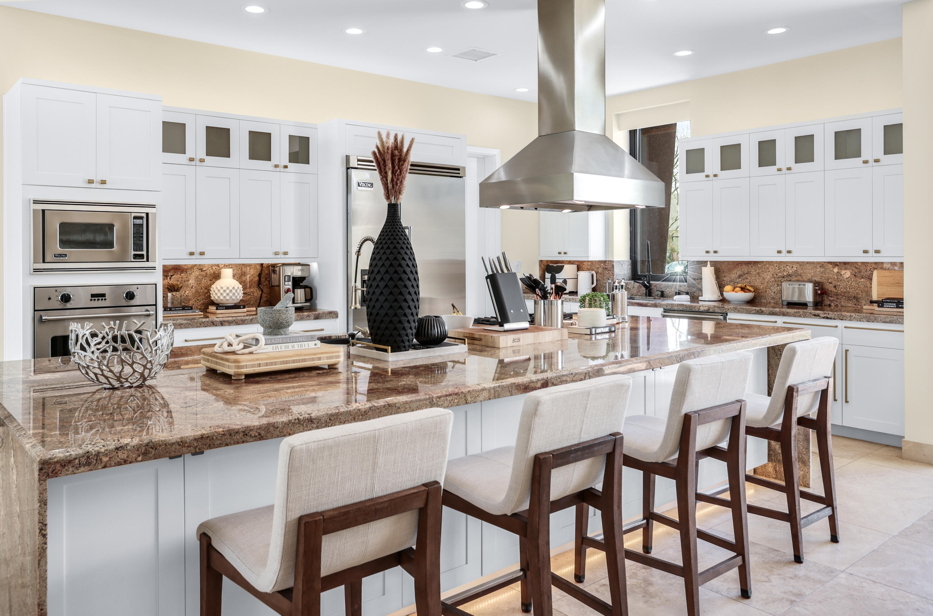 1 Seclude Court Rancho Mirage, CA 92270 - Photo 21 of 52 a kitchen with stainless steel appliances granite countertop a stove top oven a sink a dining table and chairs