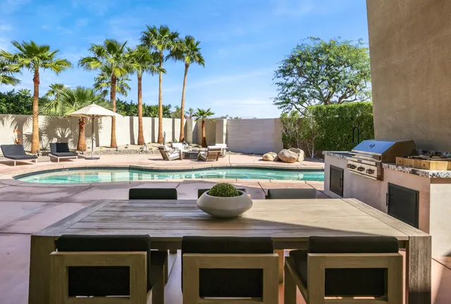 a view of a patio with couches and table and chairs under an umbrella