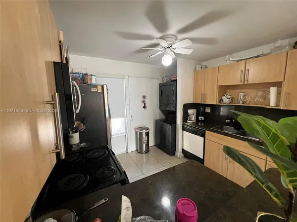 a kitchen with granite countertop a refrigerator a stove a sink and white cabinets