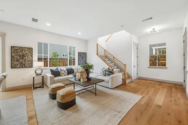 a living room with furniture and stairs with wooden floor