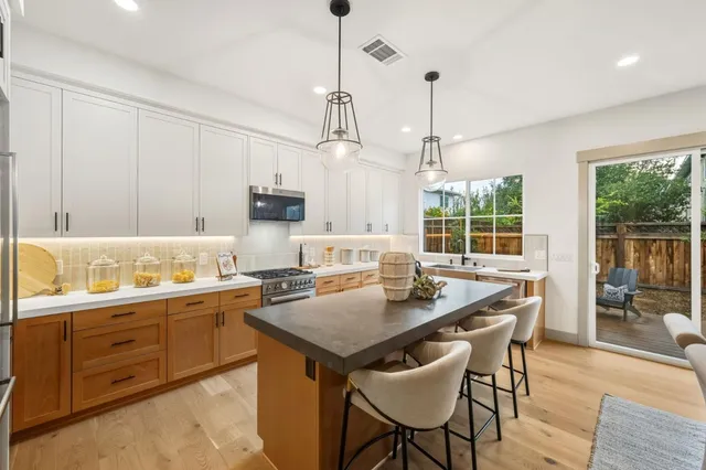 a kitchen with a stove a sink a dining table and chairs
