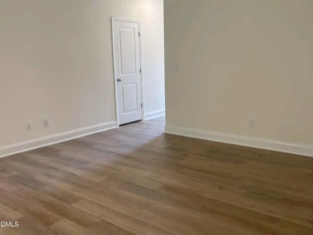 a view of an empty room with wooden floor and windows