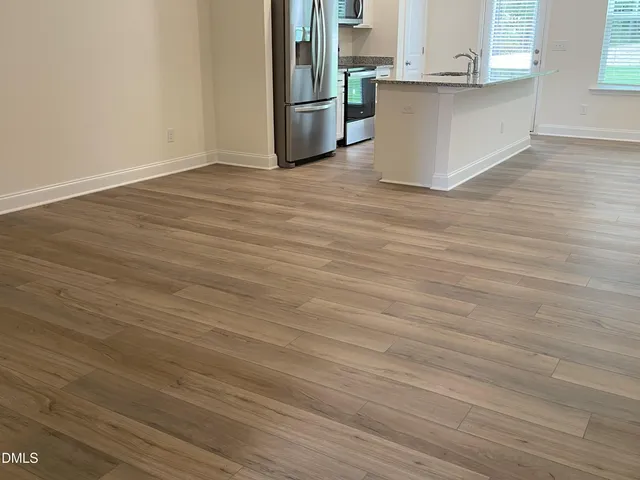 a view of kitchen with stainless steel appliances wooden floor and window