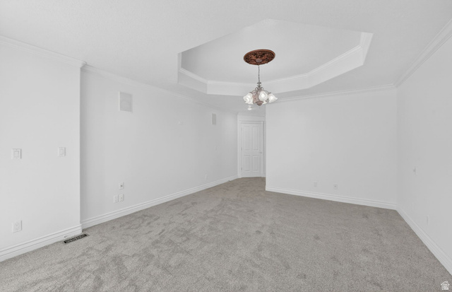 883 East 700 South Springville, UT 84663 - Photo 18 of 59 Spacious room featuring a tray ceiling with an ornate light fixture and ceiling medallion, neutral carpeting, white baseboards, and crown molding