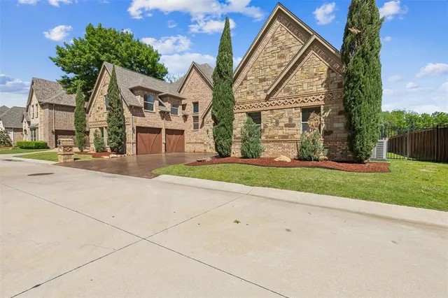 a view of a brick house next to a yard with big trees