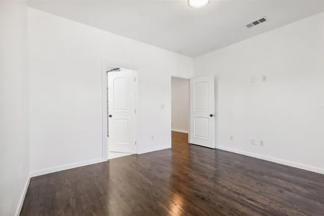 an empty room with wooden floor and mirror